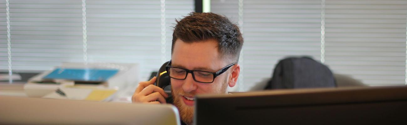 A tech support guy behind a desk.
